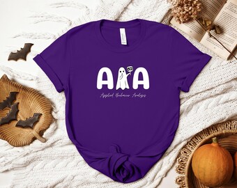 May include: Purple t-shirt with a white ghost holding a sign that says "BOO" and the text "ABA Applied Behavior Analysis".