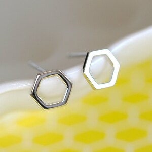 May include: A pair of silver hexagon stud earrings. The earrings are simple and modern, and they would be a great addition to any jewelry collection.