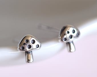 May include: A pair of silver mushroom stud earrings. The mushrooms have a dotted design.
