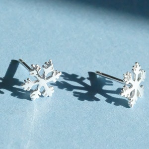 May include: A pair of silver snowflake stud earrings. The earrings are small and delicate, and they would make a great gift for someone who loves winter.