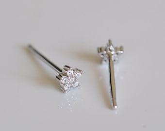 May include: Two silver-colored stud earrings, each featuring a star-shaped design. The stars are adorned with small, clear gemstones. The earrings are displayed on a white surface.