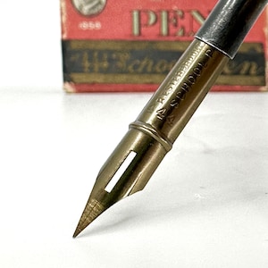 May include: A gold-toned fountain pen nib with a silver-colored metal body. The pen is labeled "14 RESTEFEDOLT 14 SCHOOL PEN".