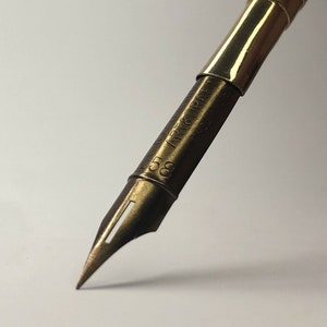 May include: A gold-toned calligraphy pen nib with the inscription "C.S.T. ART & CRAFT CO."