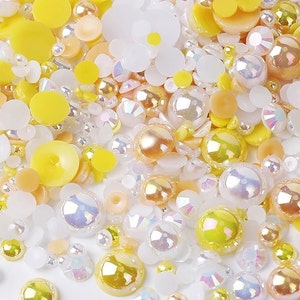 May include: A mix of white, yellow, and iridescent beads and buttons. The beads are various sizes and shapes, including round, flat, and pearlescent.