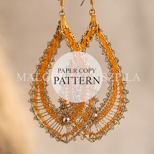 Peut inclure: Une paire de boucles d'oreilles en forme de goutte d'eau dorées et orange avec un motif de dentelle délicat. Les boucles d'oreilles sont étiquetées "PAPER COPY PATTERN".
