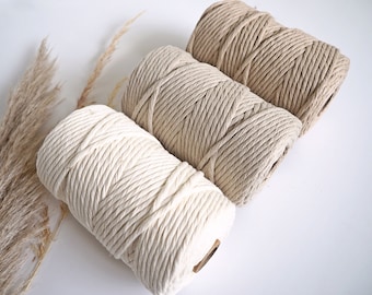 May include: Three spools of natural cotton rope in different shades of beige. The rope is thick and textured, perfect for crafting.