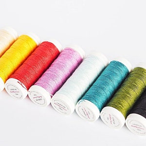 May include: A set of ten spools of thread in various colors, including cream, yellow, red, pink, light blue, teal, green, and black. The spools are labeled "Lang Yarns Catania".