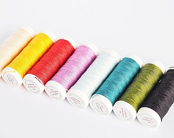 May include: A set of ten spools of thread in various colors, including cream, yellow, red, pink, light blue, teal, green, and black. The spools are labeled "Lang Yarns Catania".