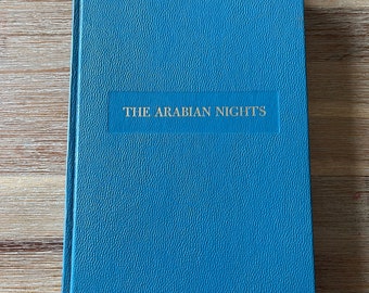 May include: A blue hardcover book with the title "THE ARABIAN NIGHTS" printed in gold lettering on the front cover.