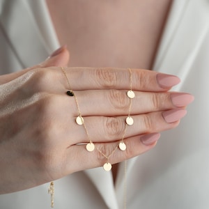 Könnte beinhalten: Eine goldene Halskette mit einer zarten Kette und mehreren kleinen runden Anhängern.