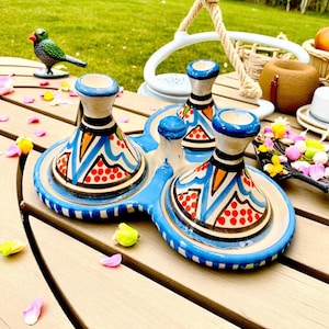 Könnte beinhalten: Ein Keramik-Servierteller mit drei Fächern, der ein blau-weißes Design mit roten Akzenten aufweist. Der Teller hat eine einzigartige Form und steht auf einem Holztisch. Eine dekorative Vogelfigur ist ebenfalls zu sehen.