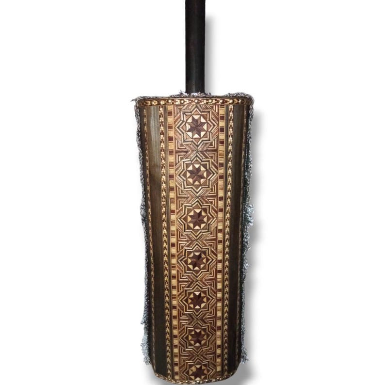 K&ouml;nnte beinhalten: Ein hoher, zylindrischer Holzbeh&auml;lter mit komplizierten geometrischen Mustern, die in Holz eingelegt sind. Der Beh&auml;lter hat eine dunkelbraune Basis und einen silbernen Fransen am oberen Rand.