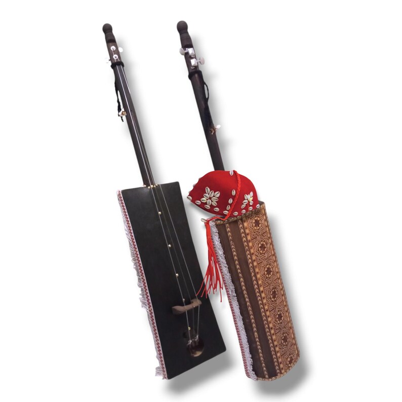 K&ouml;nnte beinhalten: Zwei traditionelle Saiteninstrumente mit Holzk&ouml;rpern und schwarz lackierten Oberfl&auml;chen. Die Instrumente haben einen langen Hals und eine einzelne Saite. Ein Instrument hat eine rote und wei&szlig;e gemusterte Stoffh&uuml;lle mit einem roten Quasten. Das andere Instrument hat eine schwarze und wei&szlig;e gefranste Stoffh&uuml;lle.