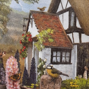 May include: A quaint cottage with a thatched roof and white walls, surrounded by lush greenery and colorful flowers. A bluebird perches on a wooden post in the foreground.