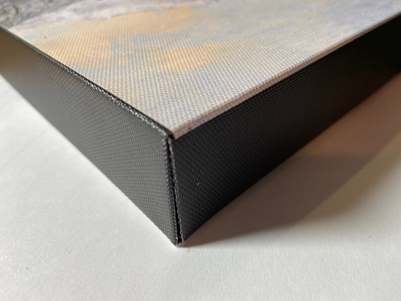 May include: Close-up of the edge of a canvas print with a black frame. The canvas is wrapped around the frame and secured with staples.