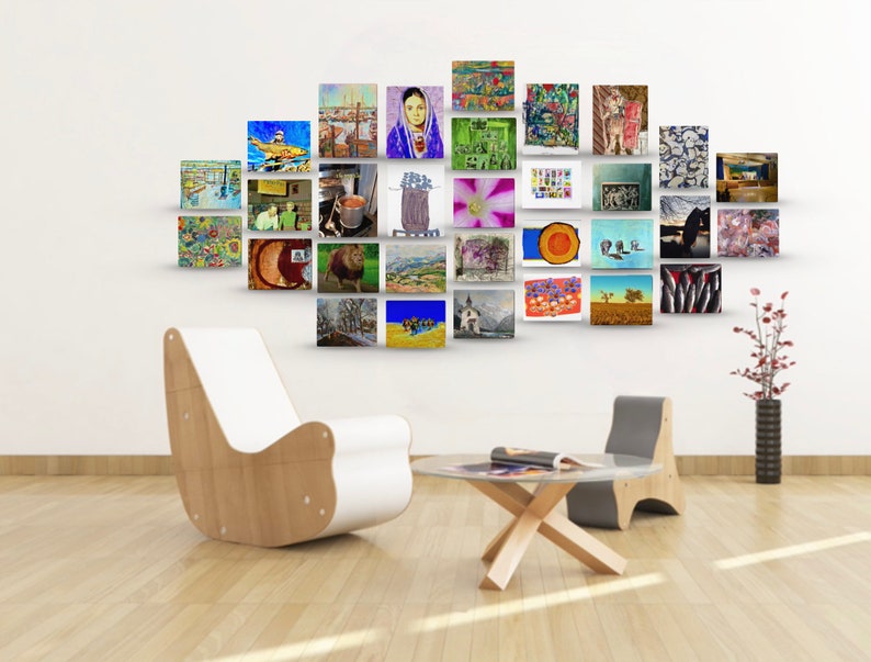 May include: A white wall with a gallery wall of framed artwork. The artwork is a mix of styles and colors, including landscapes, portraits, and abstract art. There is a white chair and a wooden table in the foreground.