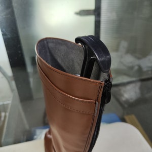 May include: Brown leather knee-high boots with a black zip up the back. The boots have a black plastic boot shaper inside.
