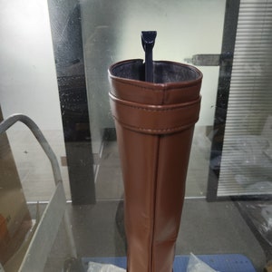 May include: A brown leather knee-high boot with a black boot stretcher inside.