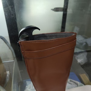 May include: Brown leather knee-high boots with a zip on the side and a black boot stretcher inside.