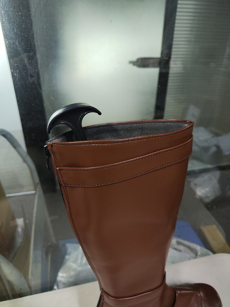 May include: Brown leather knee-high boots with a zip on the side and a black boot stretcher inside.