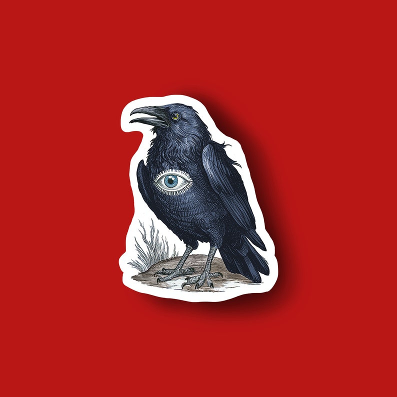 May include: A sticker featuring a detailed illustration of a black crow with an eye symbol on its chest. The crow is perched on a small mound with grass, set against a red background. The crow's eye is light blue.