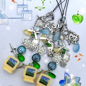 Puede incluir: Tres colgantes para teléfono con monitores de computadora beige en miniatura, dijes de teléfono móvil plateados, estrellas, cuentas de remolino azules y verdes y cuentas translúcidas en forma de lágrima en cordones negros.