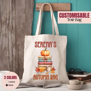Op de afbeelding: Een natuurkleurige canvas draagtas met een afbeelding van een stapel kleurrijke boeken met daarop een oranje pompoen en een mok. De tekst luidt SERENA'S AUTUMN BAG in oranje letters. De tas is voorzien van twee lange schouderbanden.