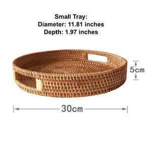 Op de afbeelding: Een ronde, geweven rotan dienblad met een diameter van 30 cm en een diepte van 5 cm. Het dienblad heeft twee ingebouwde handgrepen. De tekst op de afbeelding luidt "Small Tray".