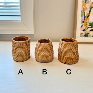 Pu&ograve; includere: Tre cesti in rattan intrecciato di diverse dimensioni. I cesti sono cilindrici con una base leggermente svasata. Il colore marrone naturale del rattan &egrave; visibile e il motivo di tessitura &egrave; ben definito. I cesti sono etichettati A, B e C.