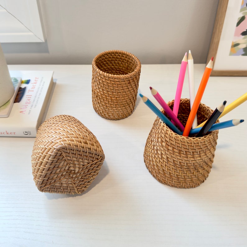 Pu&ograve; includere: Tre organizzatori da scrivania in rattan intrecciato. Un portapenne cilindrico contiene diverse matite colorate. Un secondo portapenne cilindrico &egrave; vuoto. Un terzo portapenne rettangolare pi&ugrave; piccolo &egrave; sdraiato su un lato.