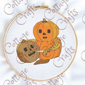 Puede incluir: Un patrón de punto de cruz con dos calabazas, una con un cuchillo en la mano y la otra con una expresión asustada. Las calabazas son naranja y marrón.