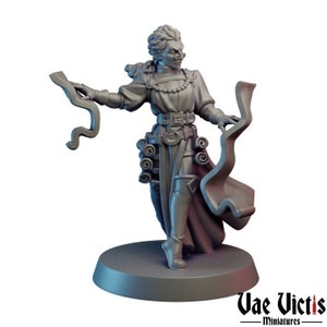 May include: A gray painted miniature figurine of a female wizard holding a scroll in each hand. She is wearing a long robe with a belt and has a beaded necklace. The miniature is standing on a round base.