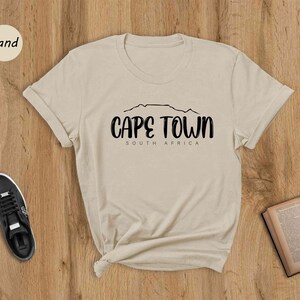 a t - shirt that says cape town on it next to a pair of shoes