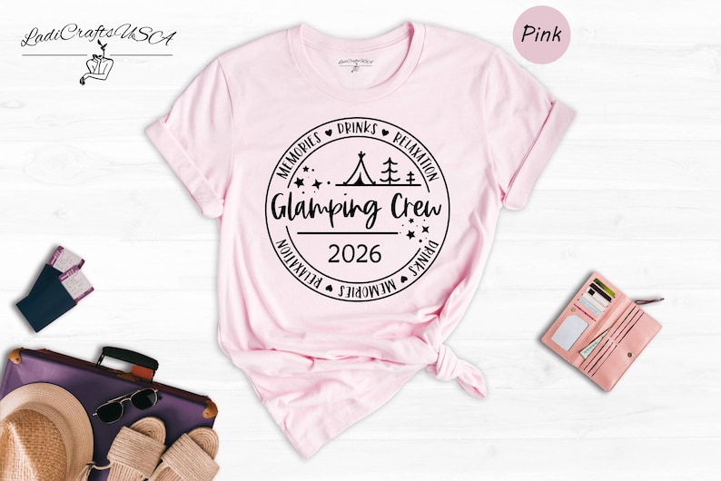 a pink t-shirt with a graphic design, a pair of sunglasses, a wallet, and a hat, all laid out on a white background.