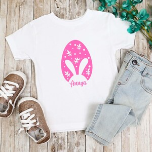 a t - shirt with an easter egg on it next to a pair of jeans
