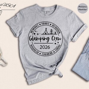 a gray t-shirt with a graphic design, a pair of jeans, and some accessories such as a pair of sneakers and a handbag.