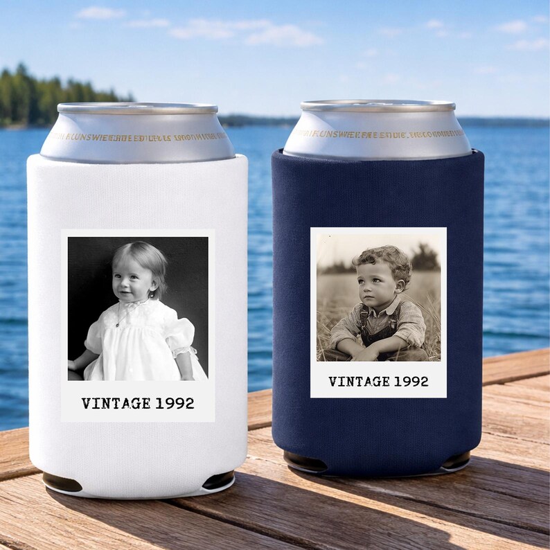 Two vintage-style can holders, one white and one blue, with black and white photographs of children on them, placed on a wooden dock overlooking a body of water.