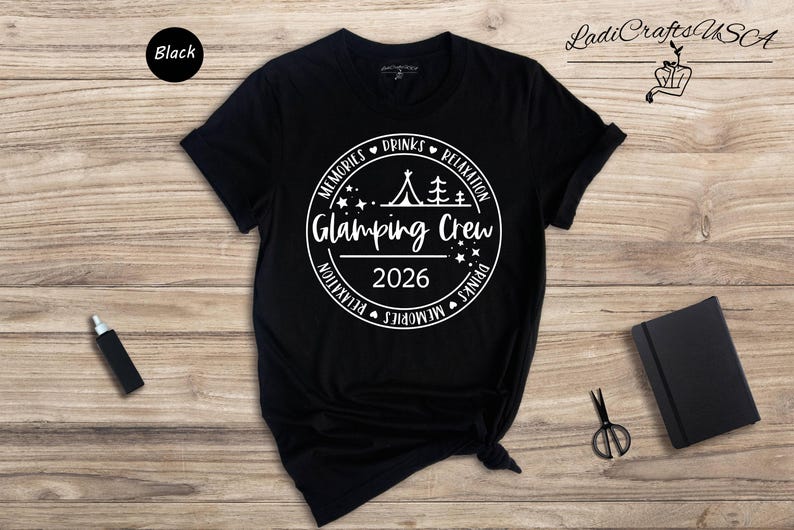 a black t-shirt with white text and graphics, along with some other items such as a black notebook, a pair of scissors, and a black bottle.