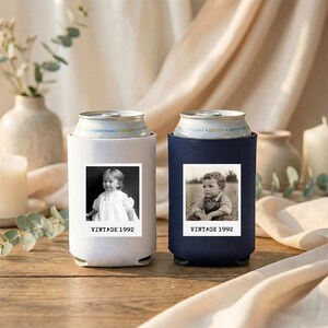 Two vintage-style can holders with black and white photographs of young children, placed on a wooden surface with candles and greenery in the background.