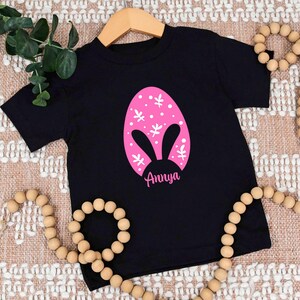 a black t - shirt with a pink bunny face on it