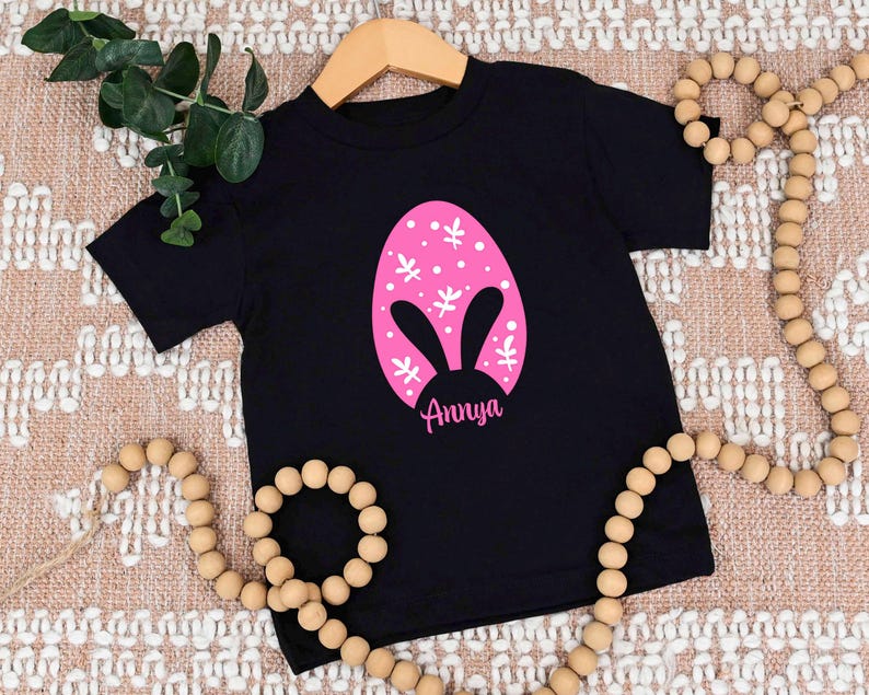a black t - shirt with a pink bunny face on it