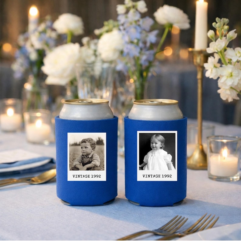 two blue can holders with vintage photographs of children, placed on a table with candles and flowers in the background.