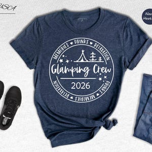A navy blue t-shirt with a white graphic design, a pair of black sneakers, and a pair of blue jeans, all laid out on a white background.