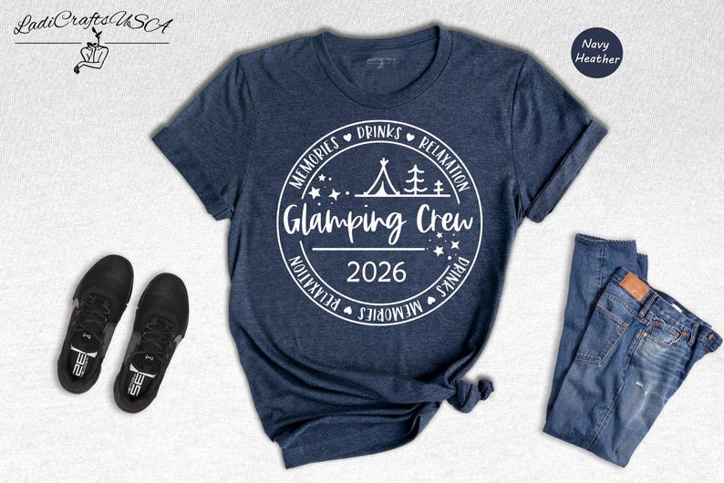 A navy blue t-shirt with a white graphic design, a pair of black sneakers, and a pair of blue jeans, all laid out on a white background.