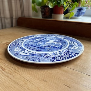 May include: A blue and white ceramic cake plate with a floral design and a central scene of a building and trees.
