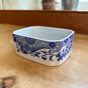 以下が含まれることがあります： 青と白のフローラルパターンが施された白いセラミック製の四角い皿。皿は長方形で、わずかに丸みを帯びた縁があります。