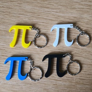May include: Four keychains shaped like the mathematical symbol pi, each in a different colour: yellow, white, blue, and black. The keychains are attached to silver key rings.