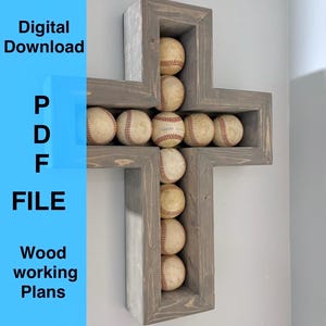 Op de afbeelding: Een grijze, houten, kruisvormige honkbaldisplay met meerdere honkballen. De honkballen zijn wit met rode stiksels. De tekst "Digital Download PDF FILE Wood working Plans" staat op een blauwe achtergrond.