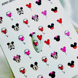 Könnte beinhalten: Ein weißer Bogen mit Nagelaufklebern, die verschiedene Mickey- und Minnie-Maus-Köpfe, Silhouetten und Luftballons in Rot, Pink und Schwarz zeigen. Der Text BEARS CUSTOM CLAW'S steht oben links, in der Mitte liegt eine mandelförmige Nagelspitze.