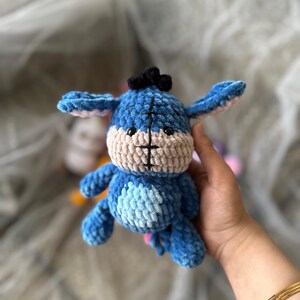 以下が含まれることがあります： 黒い髪の房が付いた、手作りの青と茶色のぬいぐるみロバのおもちゃ。 ぬいぐるみは、明るい青色の体、明るい青色のお腹、茶色の顔をしています。 ロバの耳は、ピンクの内耳が付いた明るい青色です。